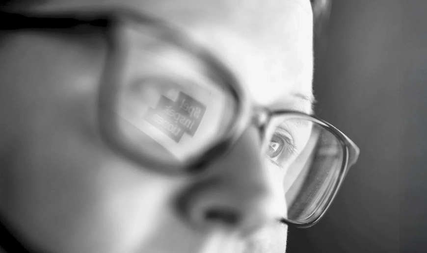 Närbild av kvinna med glasögon där Spelinspektionens logotyp syns i skärmreflektionen